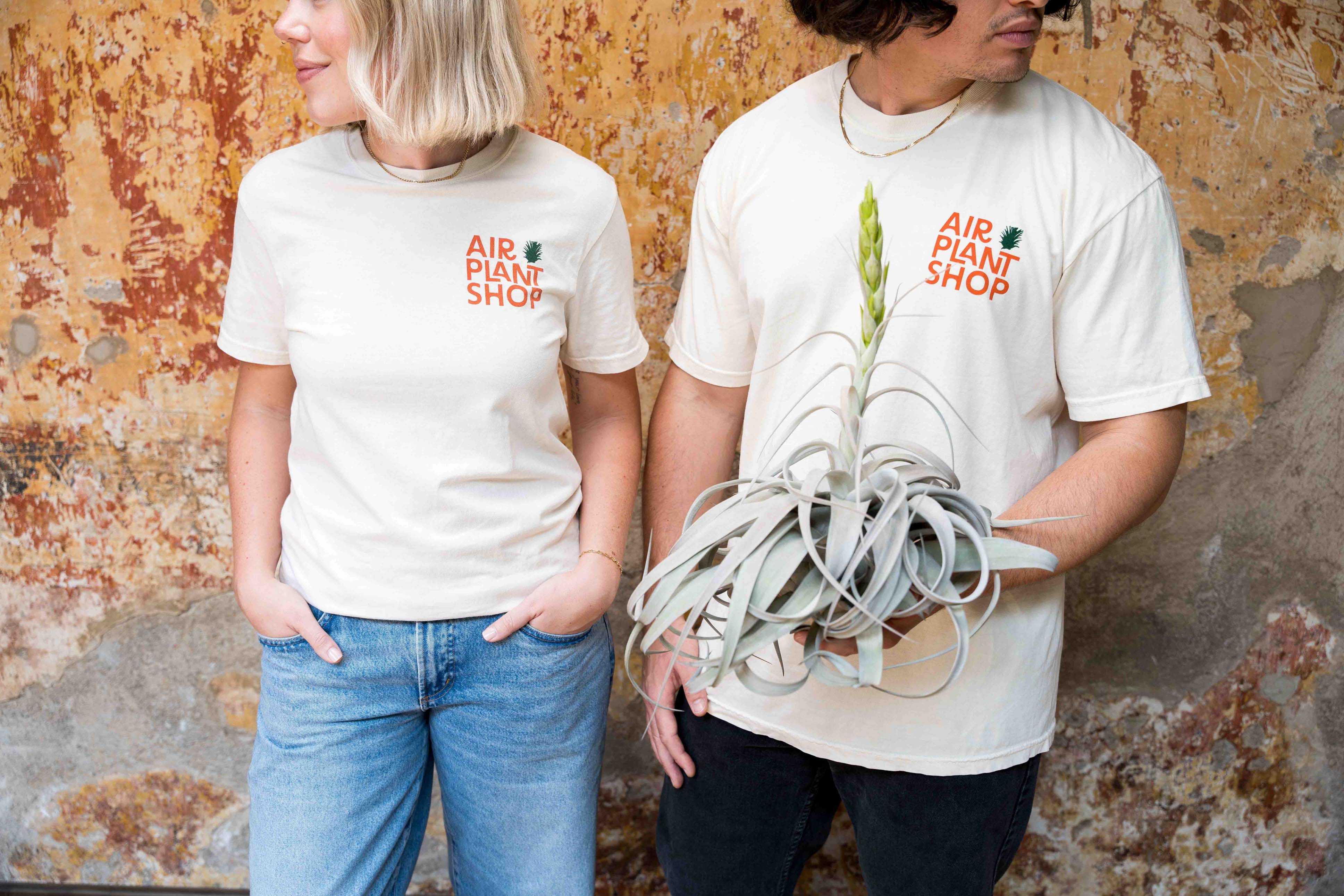 man and woman wearing air plant shop shirts, showing front