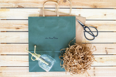 branded gift bag, glass mister and brown crinkle paper